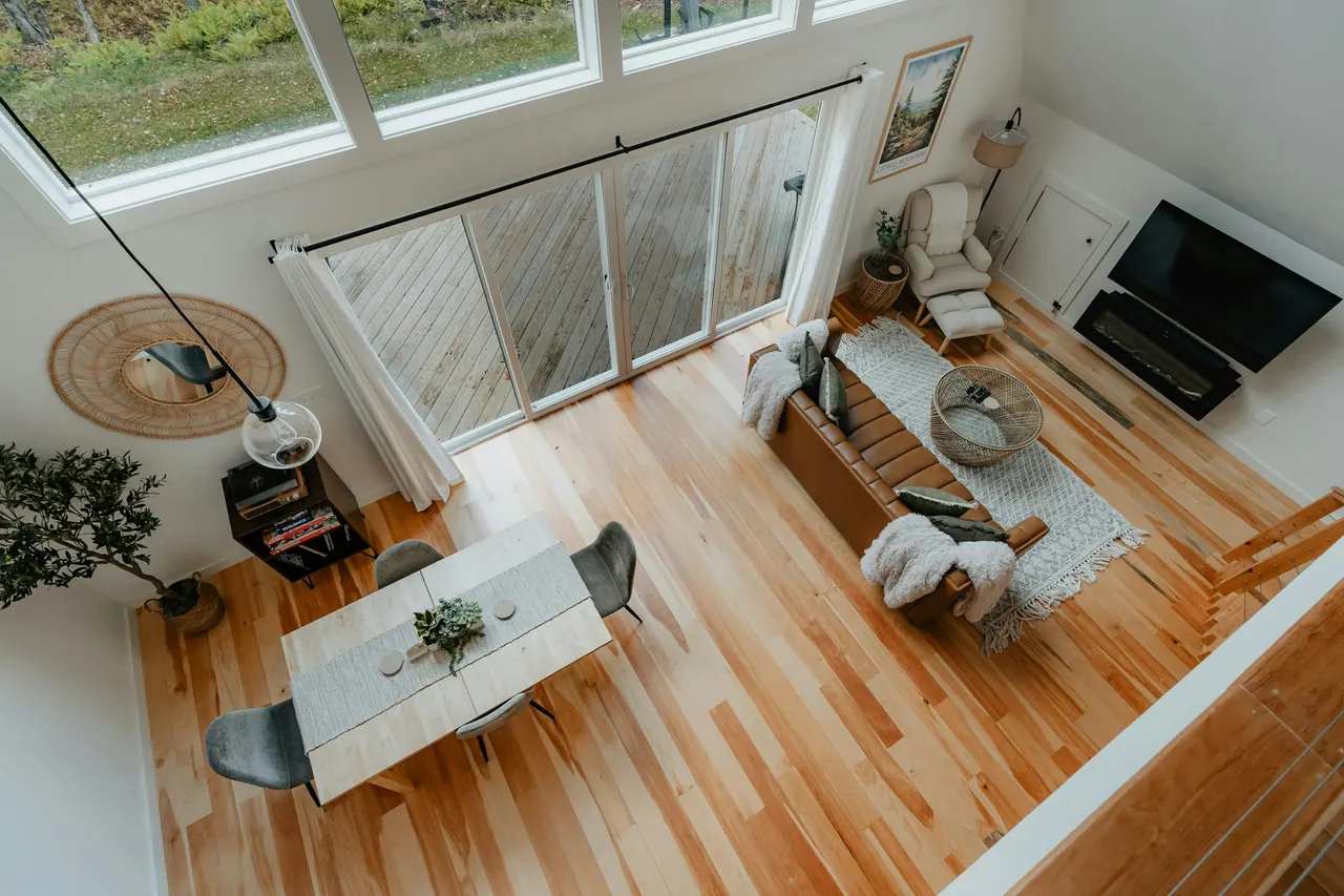 An open plan living and dining room on honey wood floors, seen from above