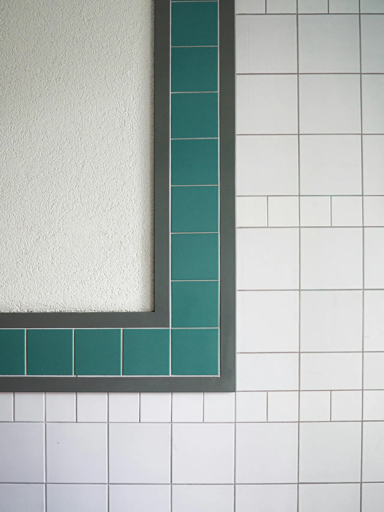 A teal tile border framing white square tiles