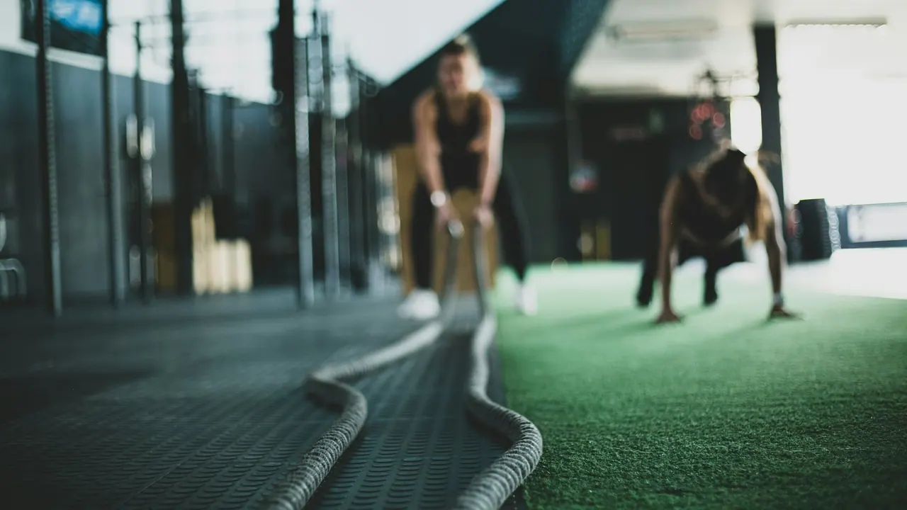 Two members training with ropes on a turf lane