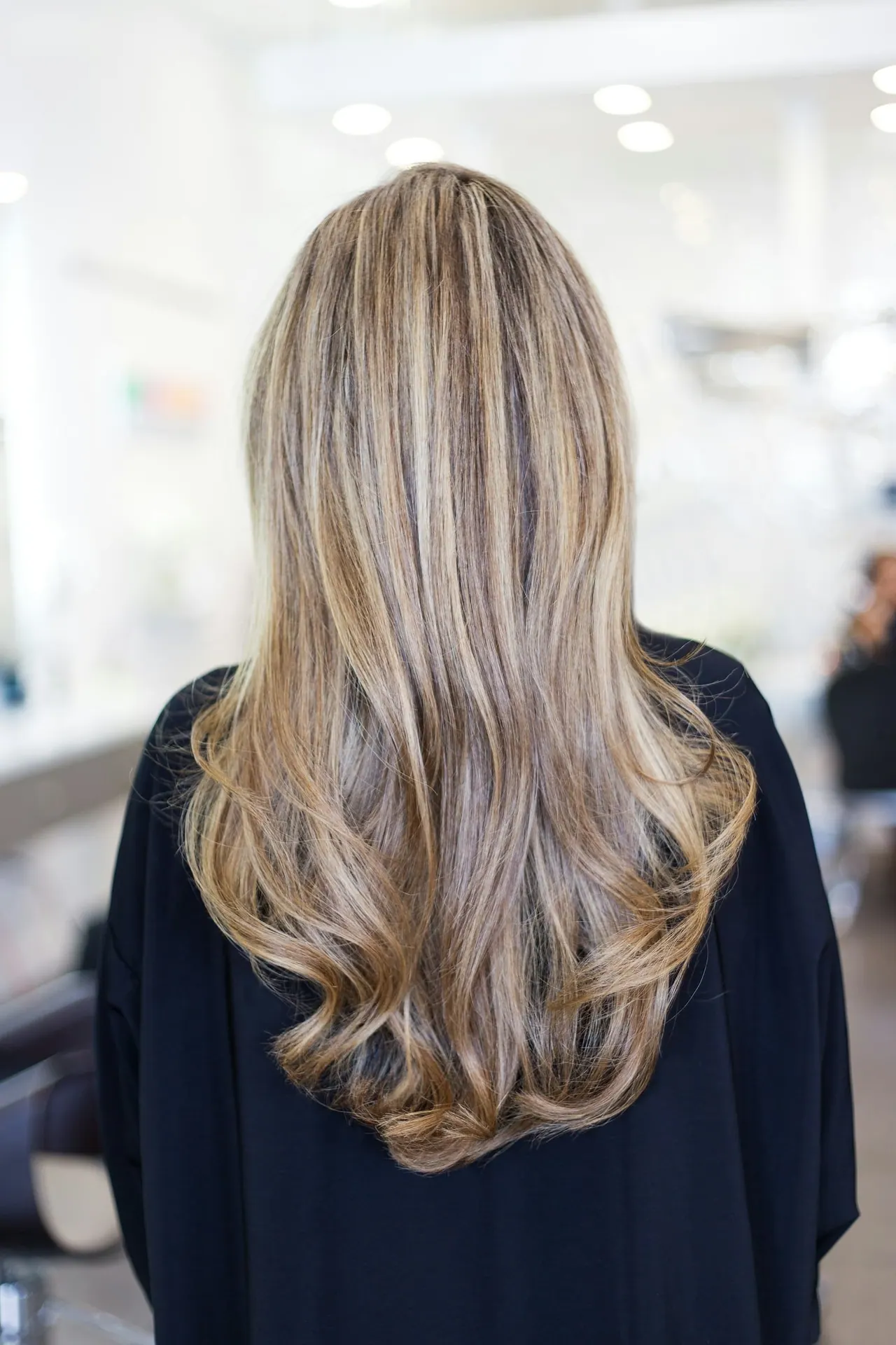 Long glossy blonde hair with soft curled ends, seen from behind