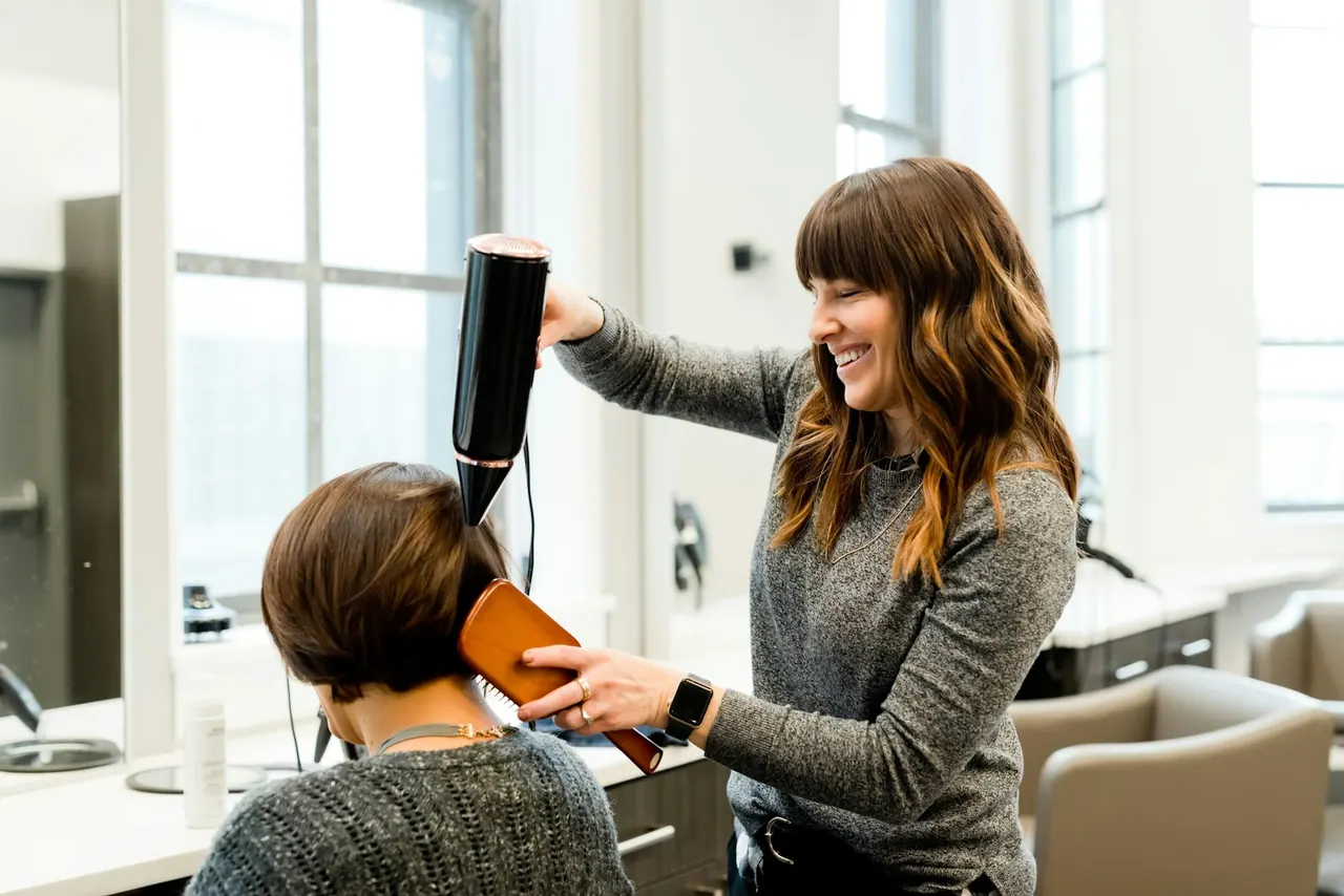 The creative director smiling while blow drying a client’s bob