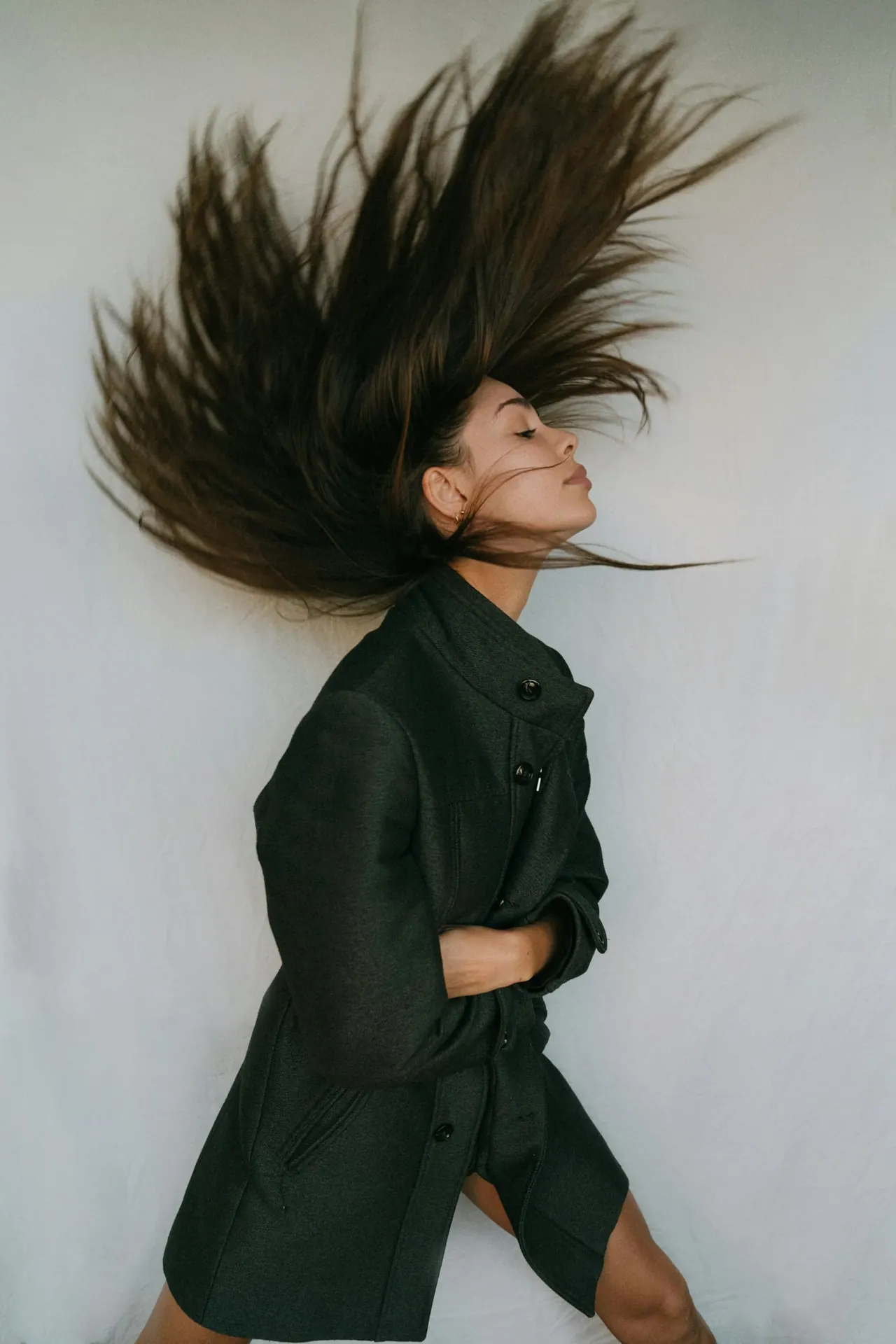 A woman in black flicking her long dark hair