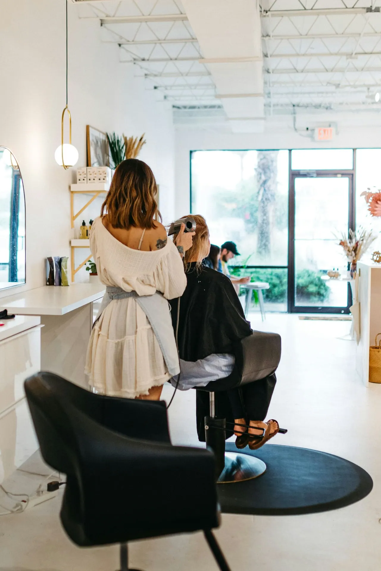 A stylist working with a client in a bright white salon