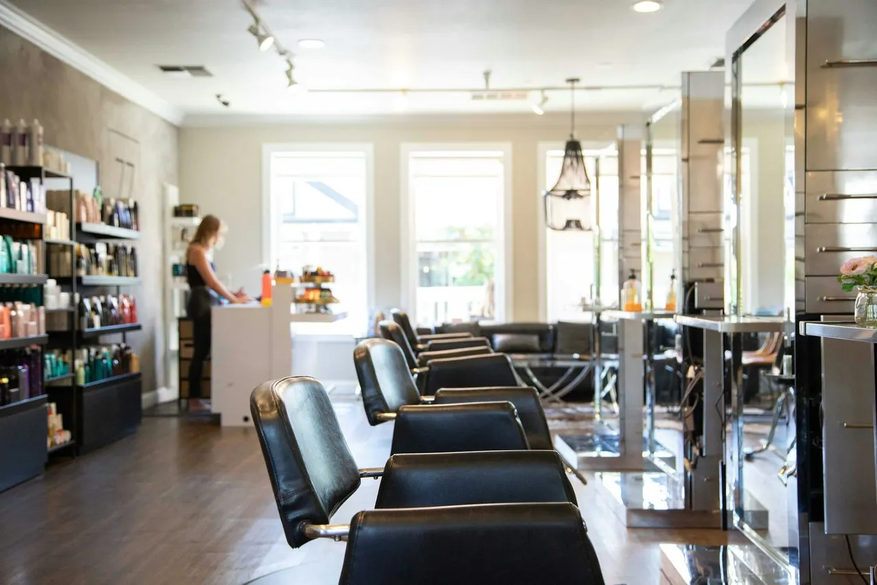 A long, sunny salon with rows of styling chairs