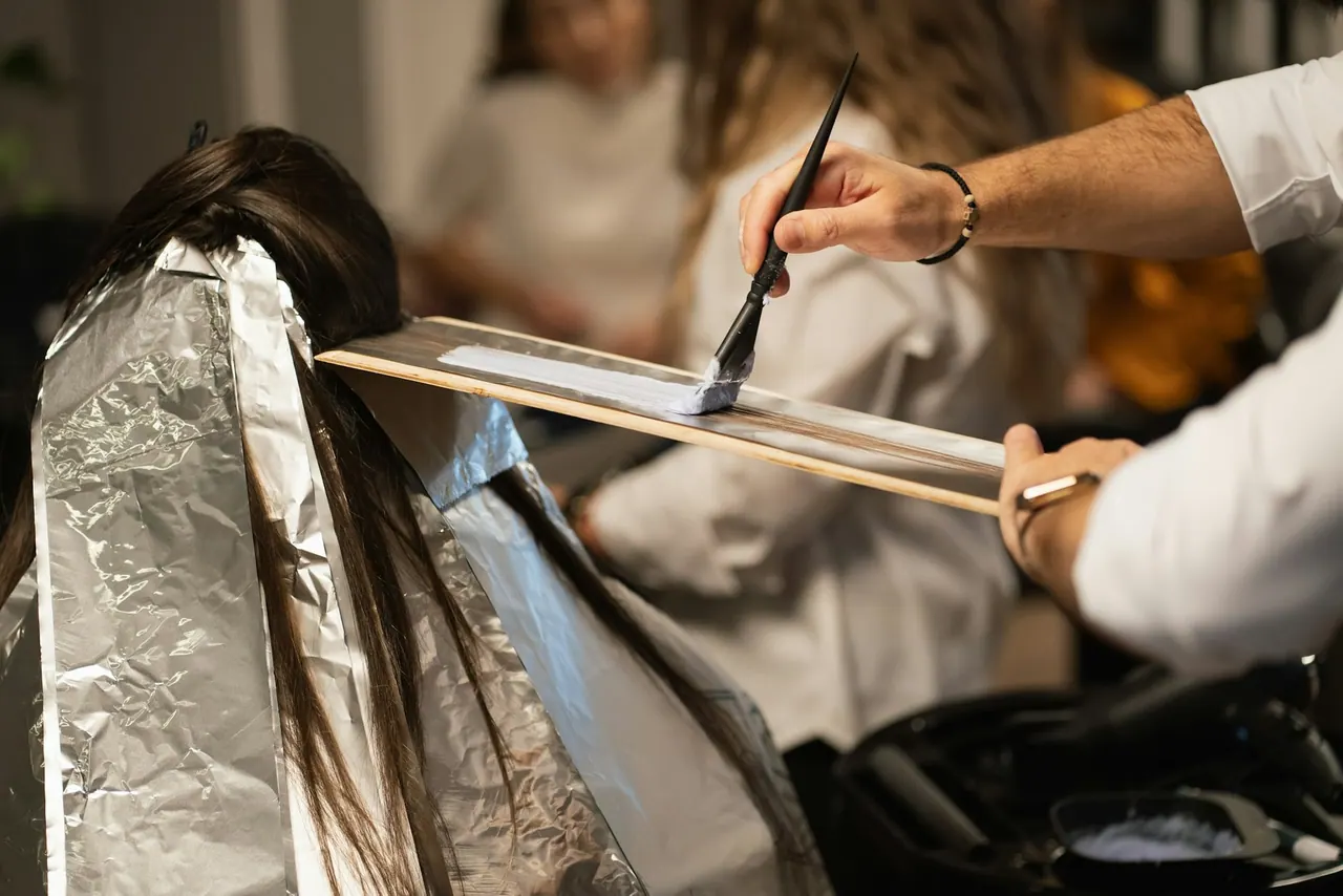 A colourist painting lightener onto foiled sections of hair