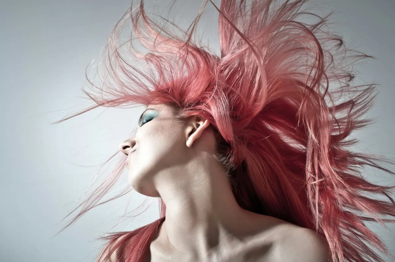 A woman tossing bright pink hair in motion