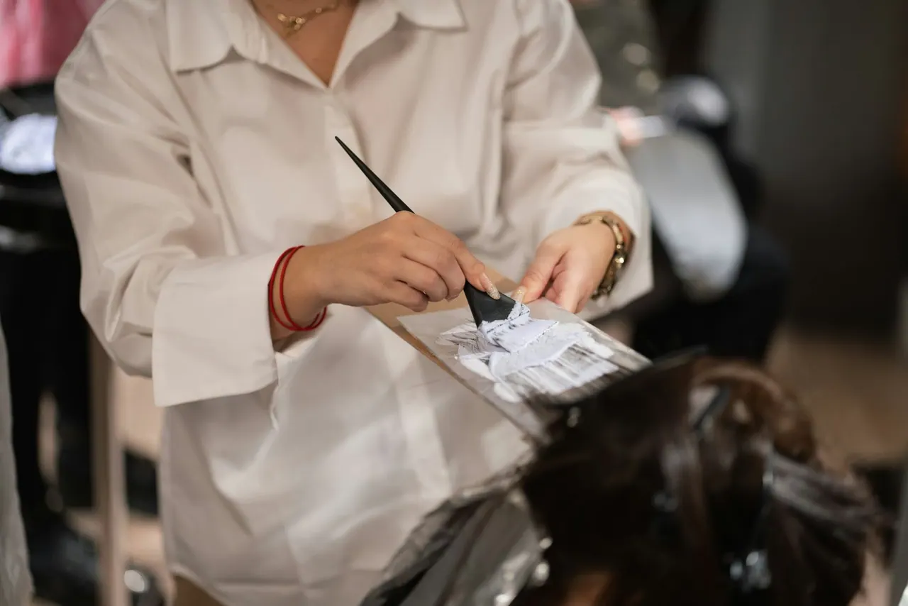 A colourist in a white shirt painting colour onto foils