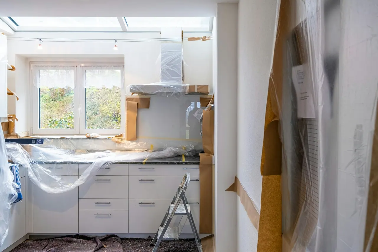 A kitchen mid repair, its cabinets wrapped in protective film