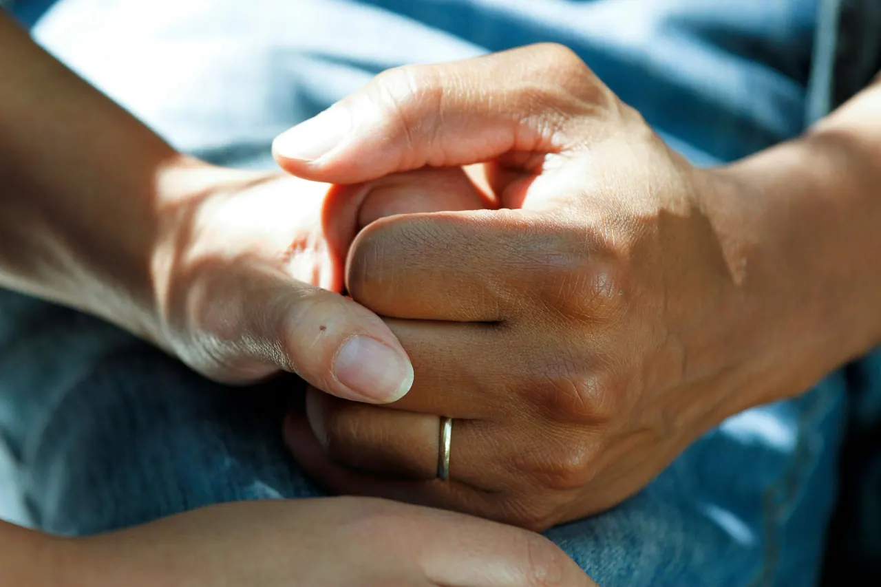 A caregiver gently holding an older person’s hands
