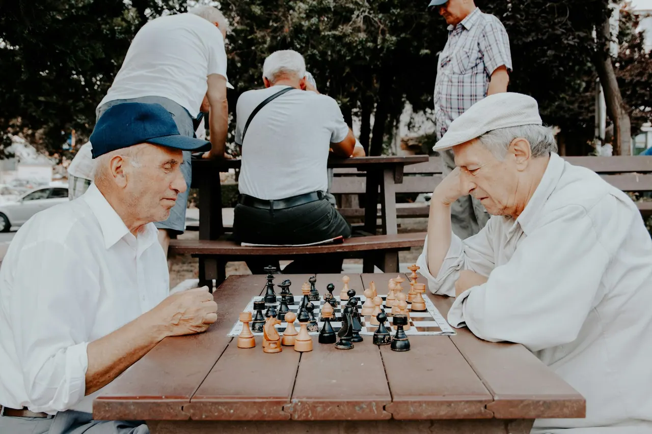 Two older men concentrating over a game of chess in the park