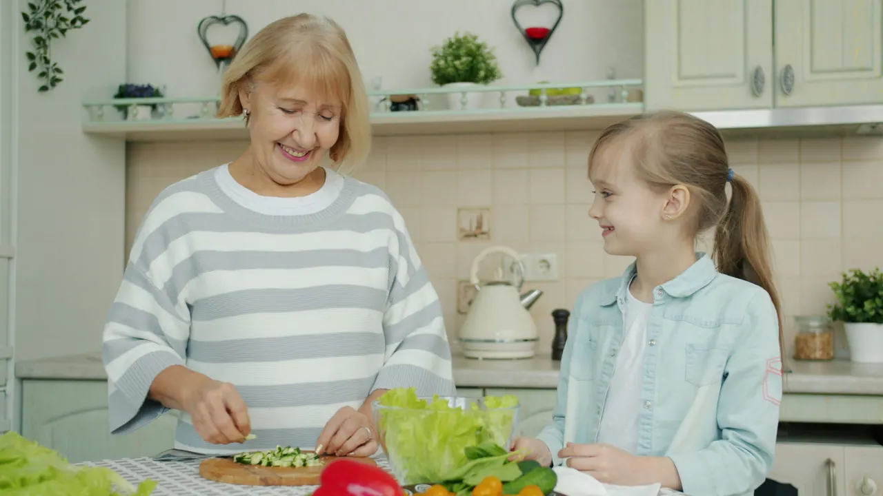 A grandmother and granddaughter making a salad together at home
