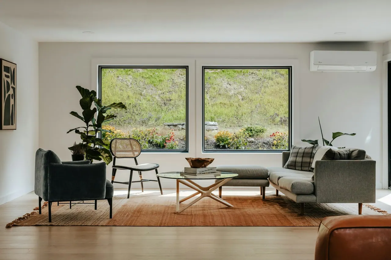 A bright living room with large windows and a wall mounted heat pump