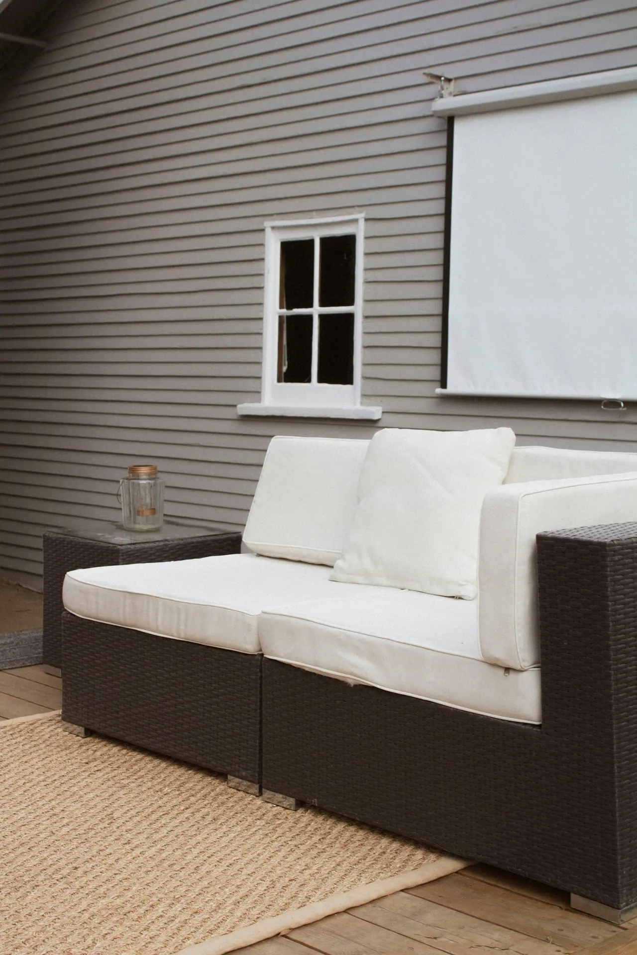 A white outdoor sofa on a wooden patio beside a house
