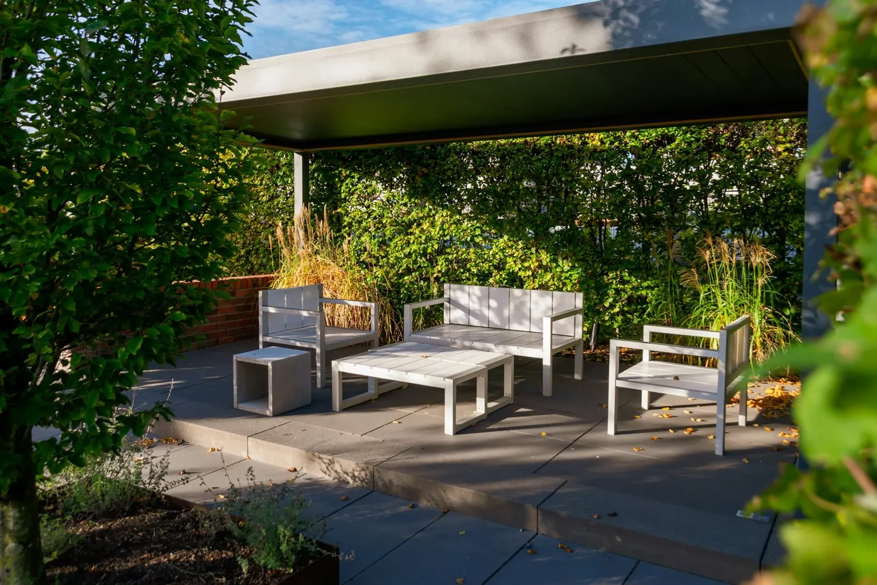 A covered terrace with outdoor sofas surrounded by planting