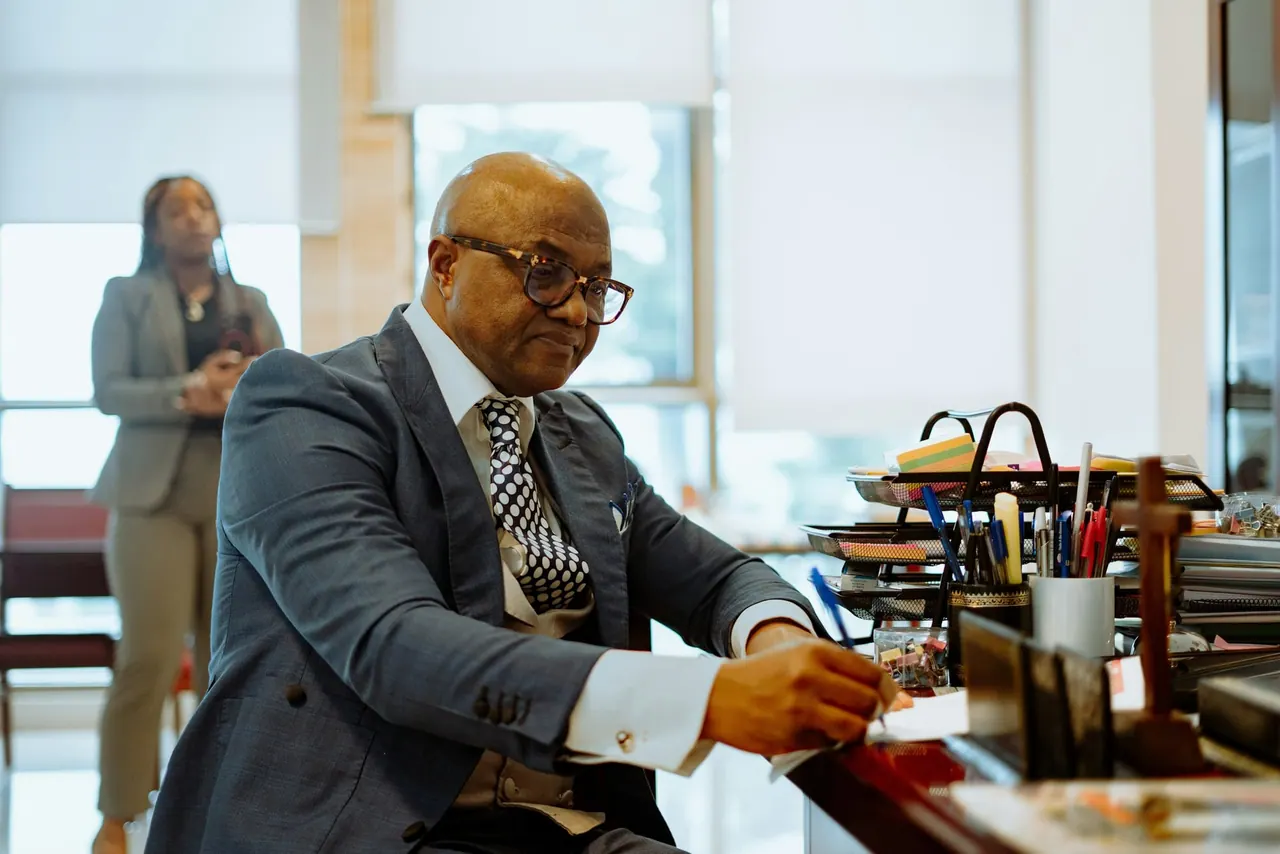 A senior lawyer in glasses signing papers at his desk