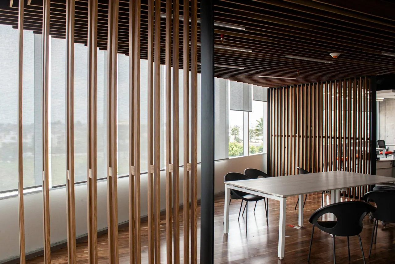 Our office, with tall wooden slats and a long meeting table by the windows