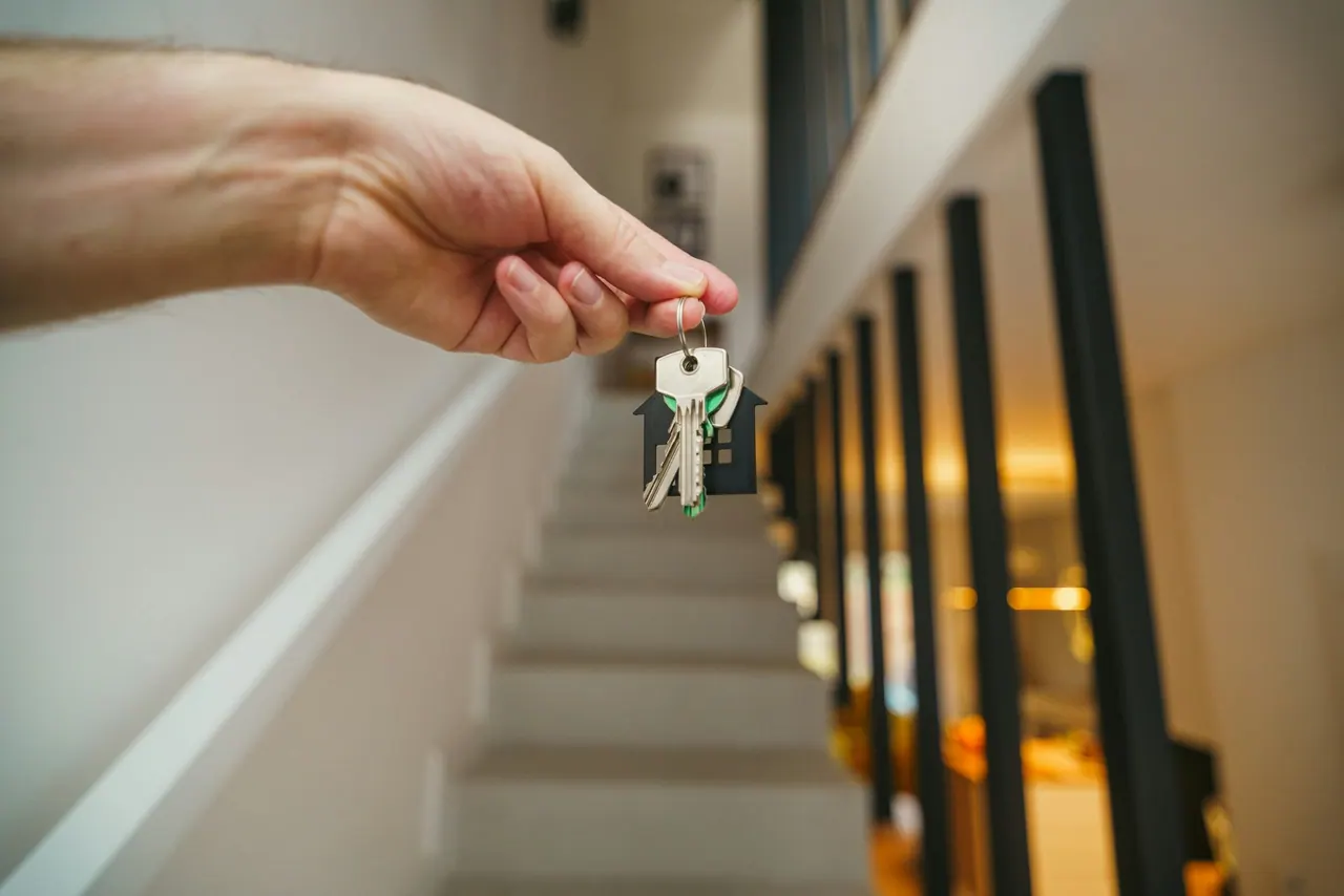 A hand holding a bunch of house keys at the top of a bright stairwell
