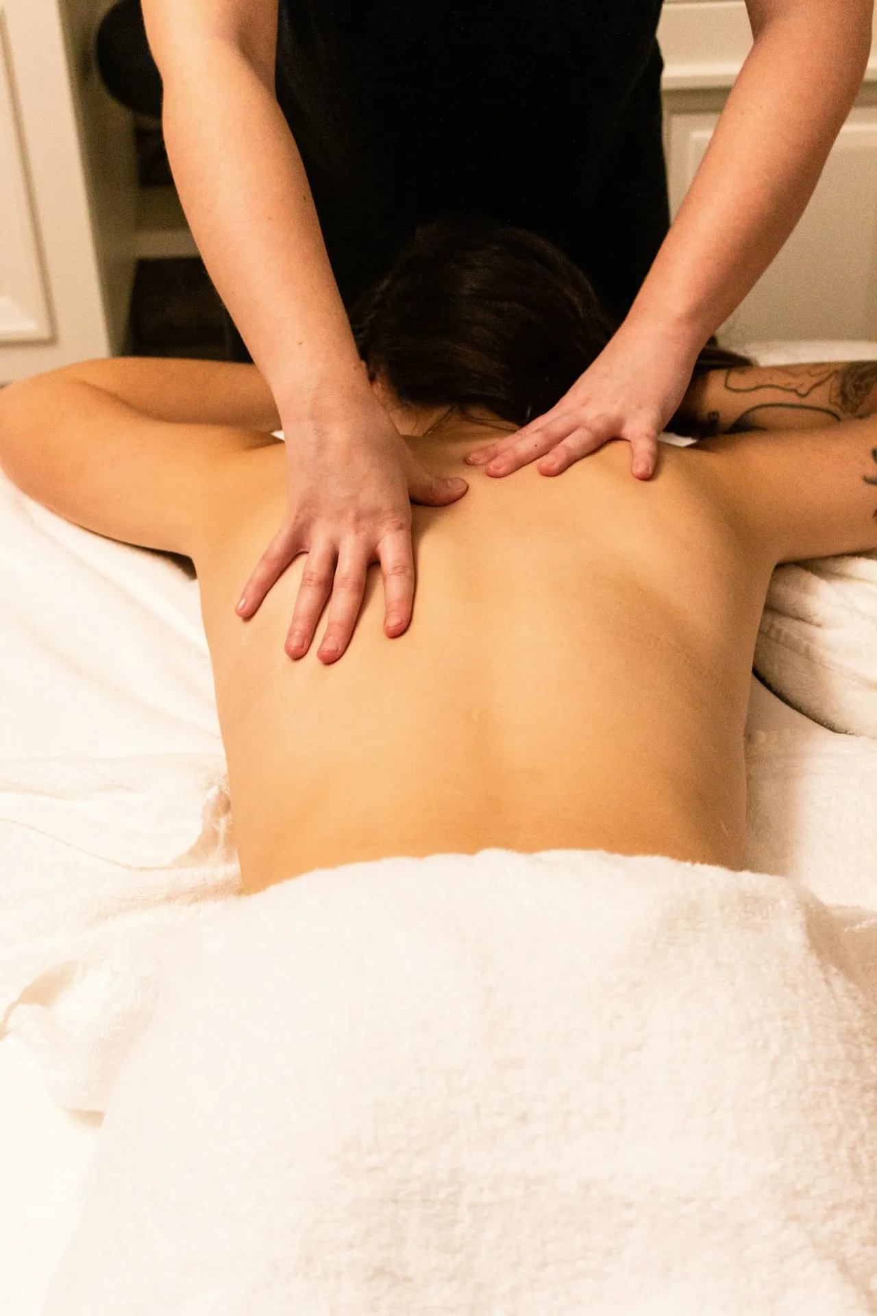 A therapist massaging a client’s upper back and shoulders