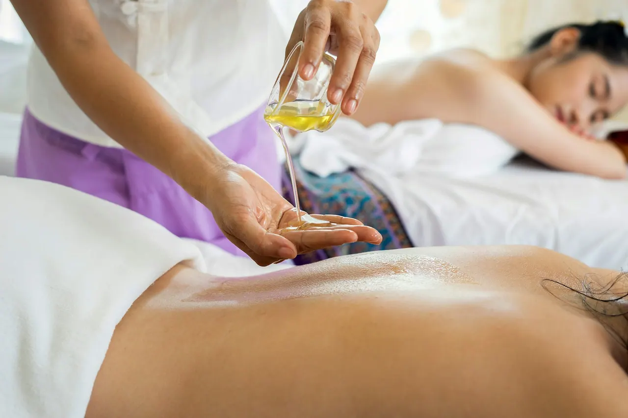A therapist pouring warm oil before a back massage
