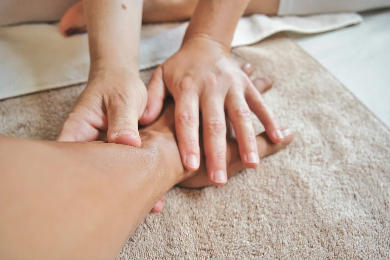 Hands working firmly along a client’s forearm