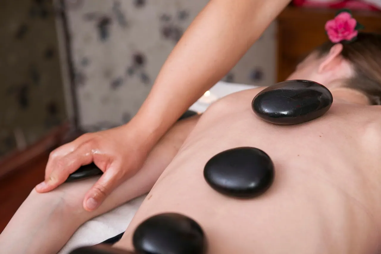 A therapist placing smooth hot stones on a client’s back
