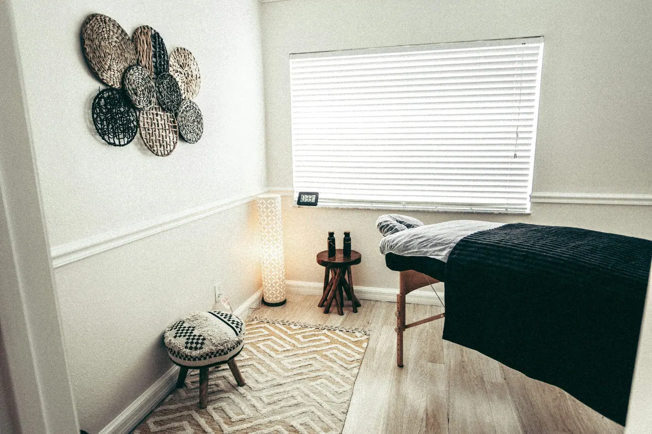 A calm treatment room with a massage table, a lamp and a patterned rug