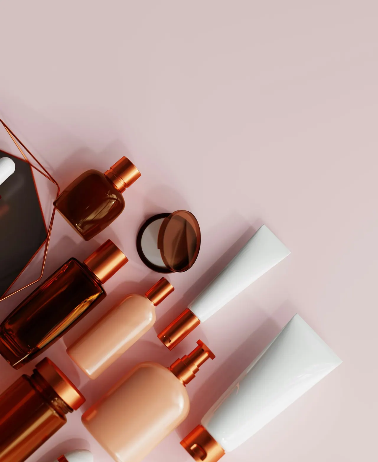 Rose gold skincare bottles and tubes laid out on a soft pink surface