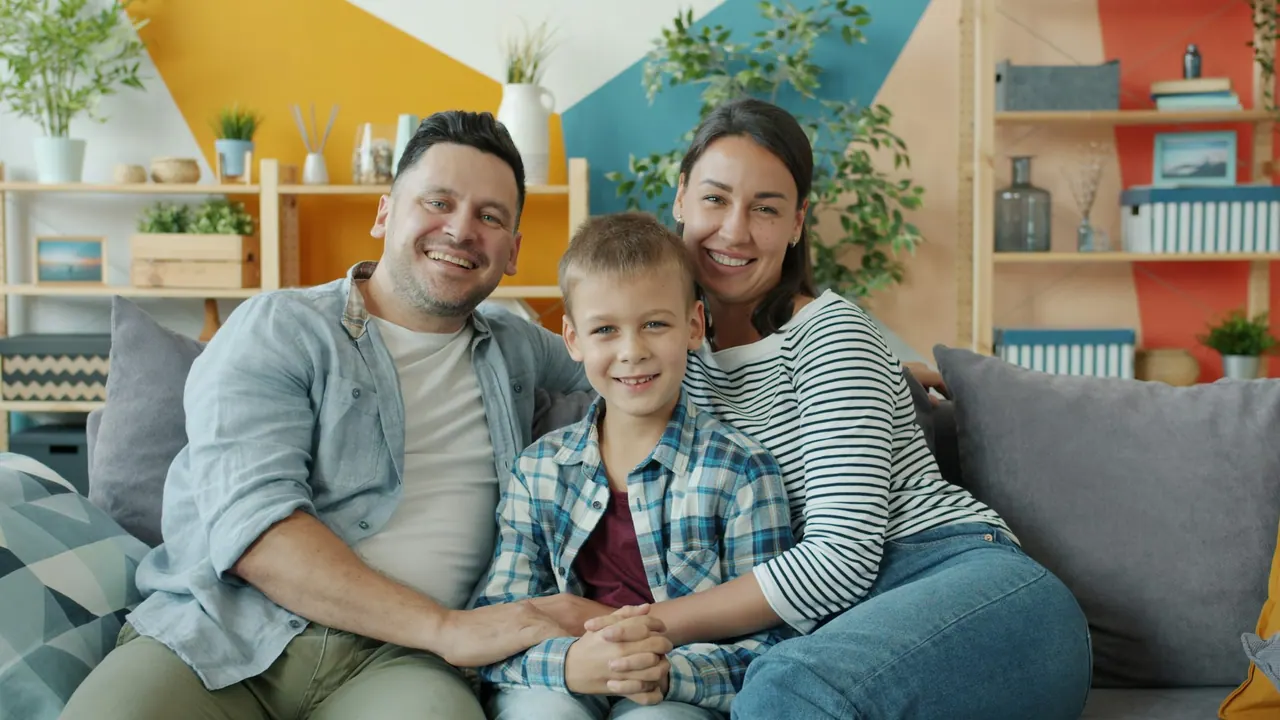 A smiling family of three on the sofa in their living room