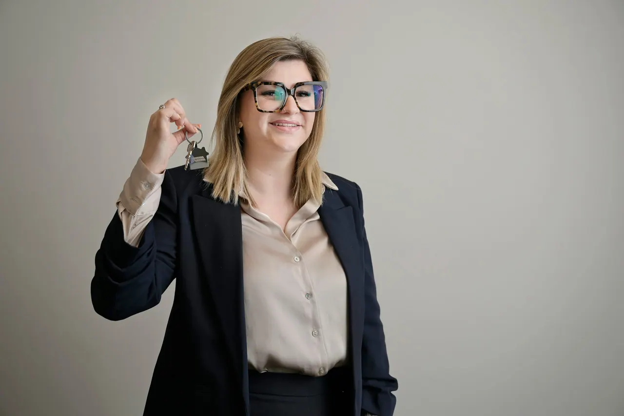 A smiling mortgage broker holding up a set of house keys