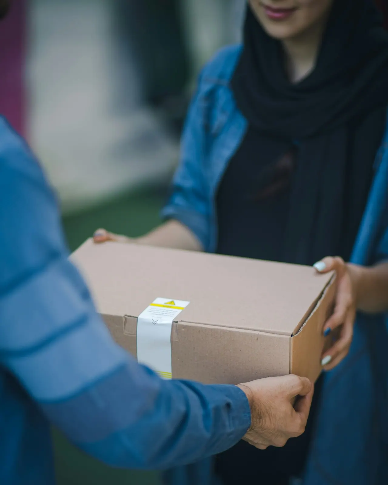 Two people handing over a taped cardboard box