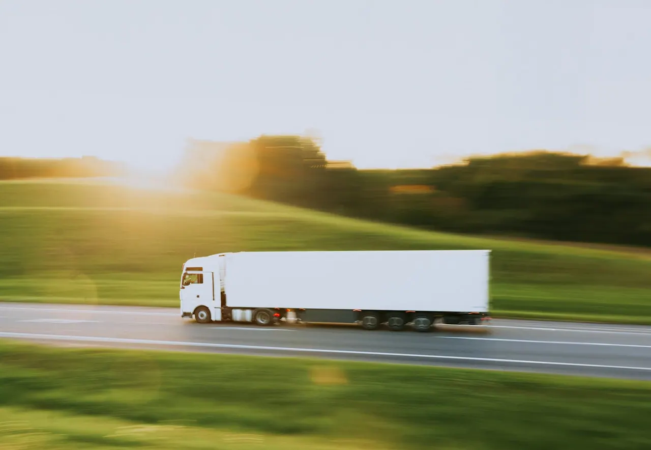 A white truck on a green country road at golden hour