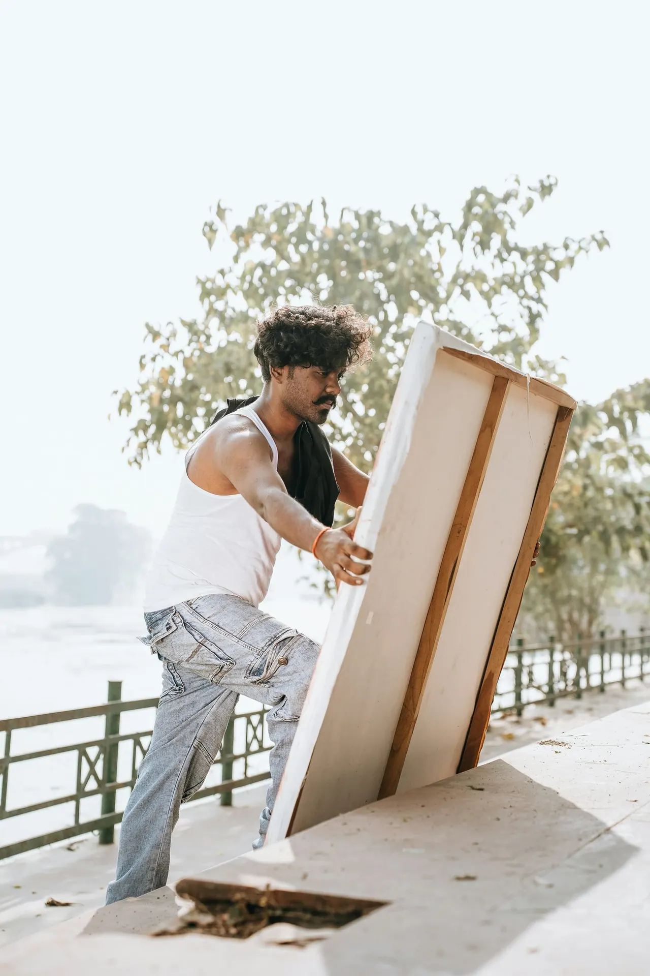 A mover lifting a large framed picture outdoors