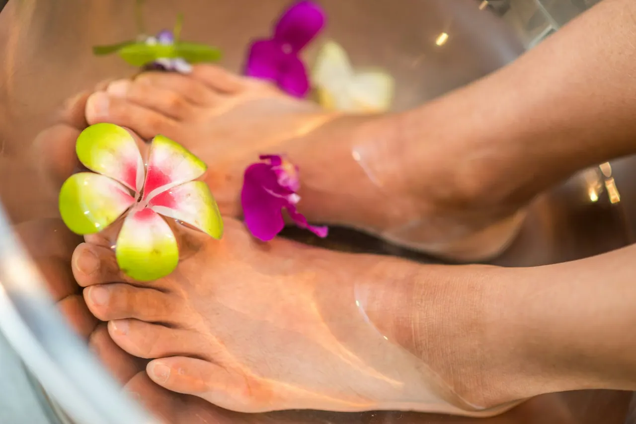 Feet soaking in a pedicure bowl with orchids