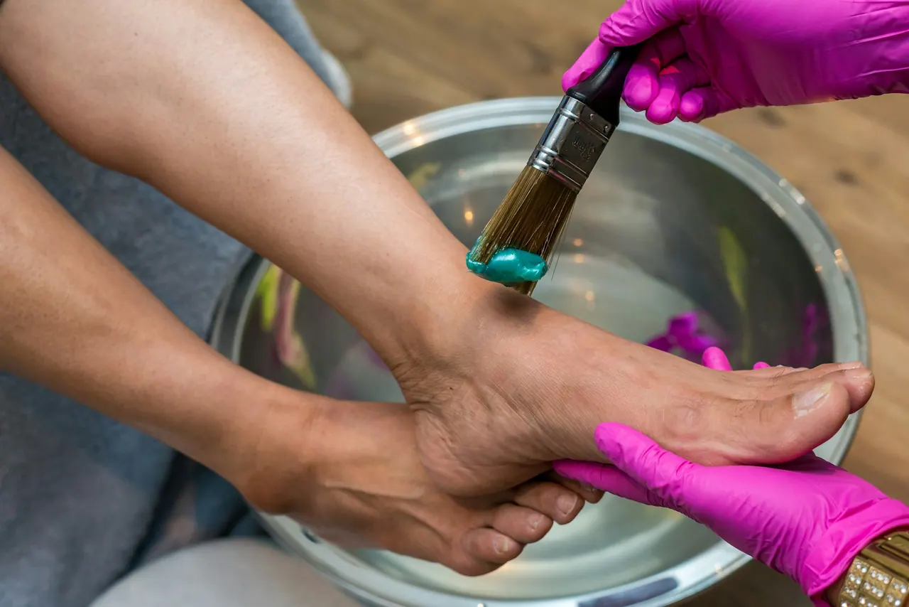 A gloved technician painting toenails over a footbath