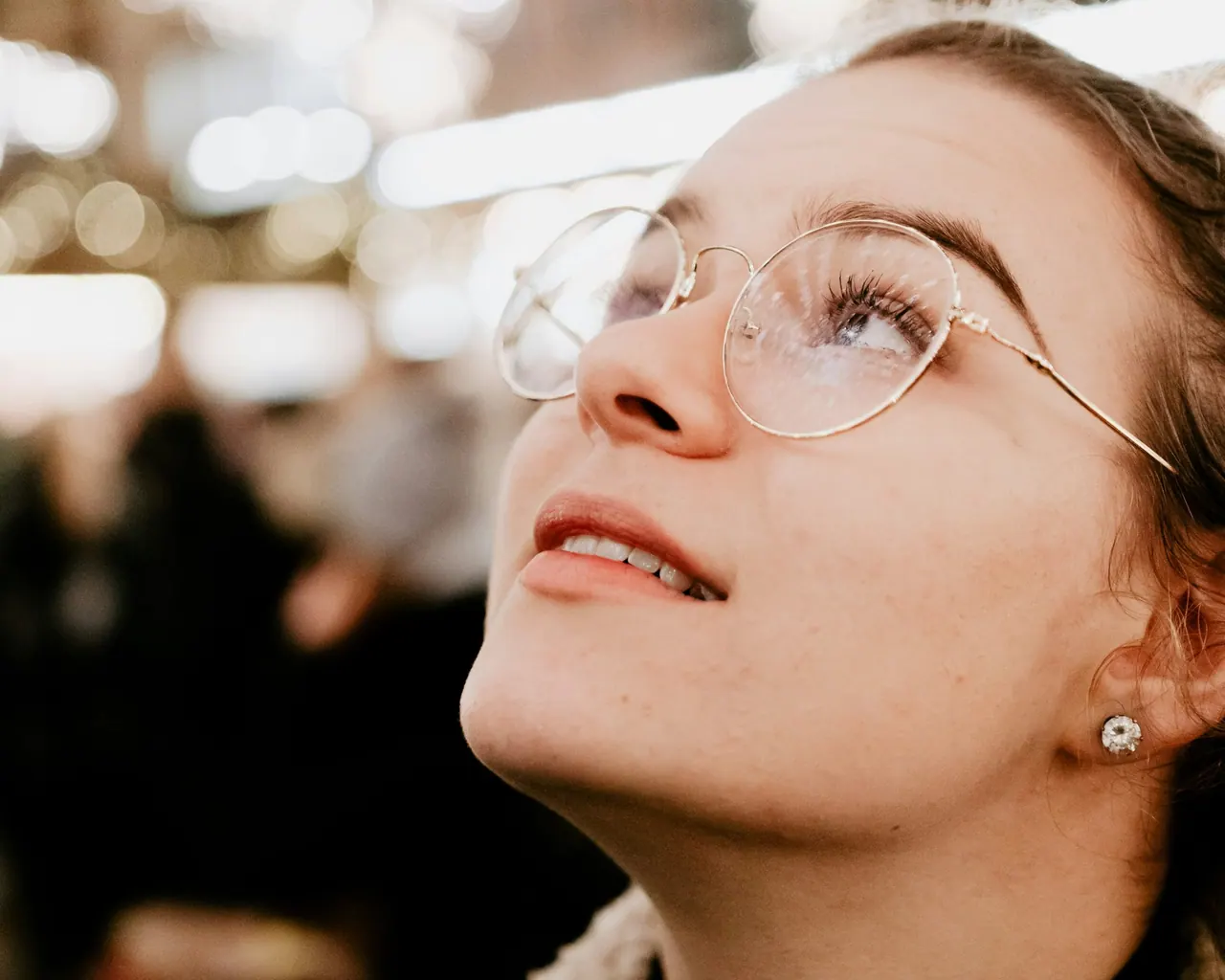 A woman in thin gold glasses looking up and smiling