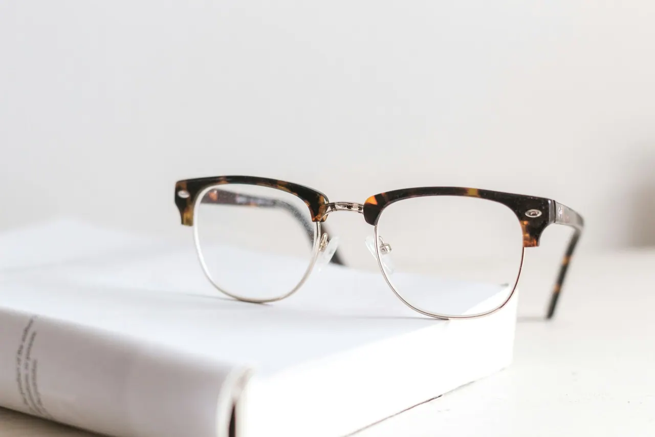 Browline glasses with a tortoiseshell top resting on a white book