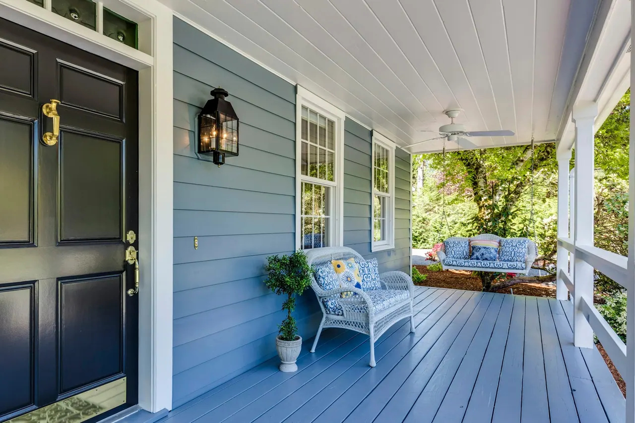 A blue porch with repaired boards and white wicker chairs