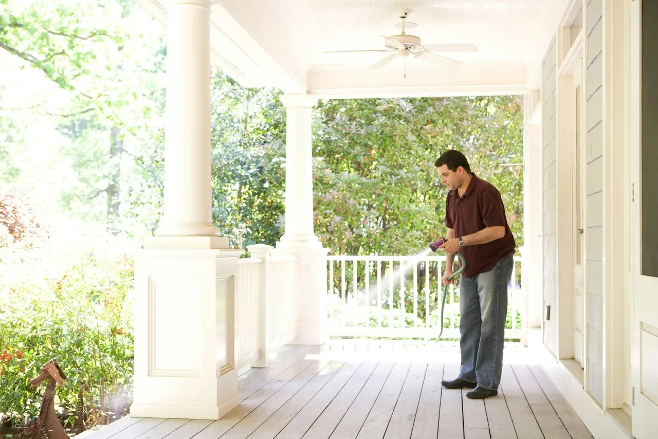 A technician treating the edge of a wide front porch
