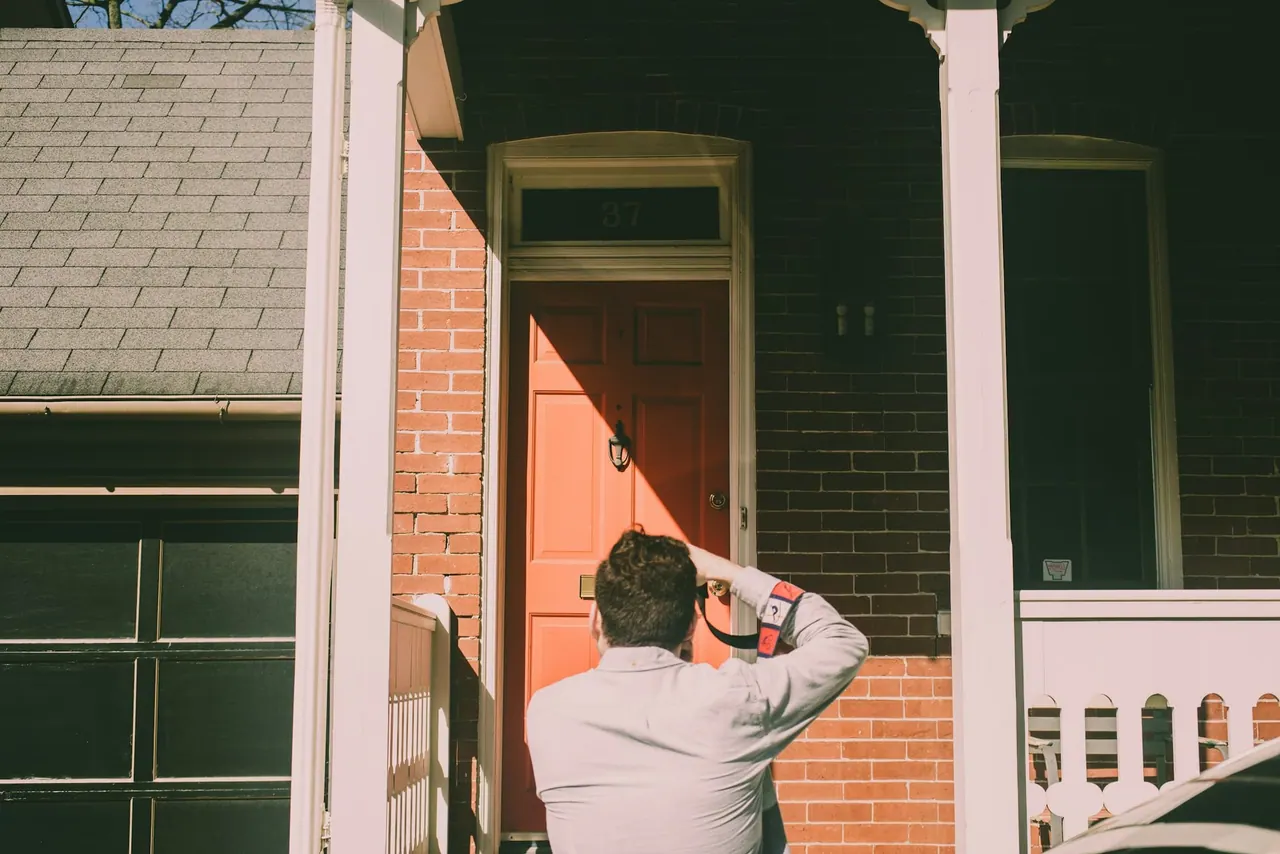 An inspector checking the front door frame of a brick house