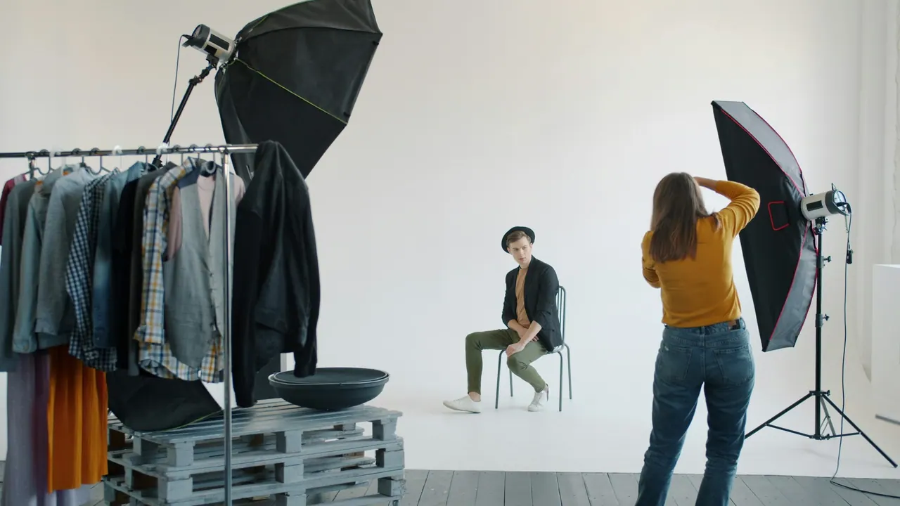 A photographer directing a model on a chair in a bright studio