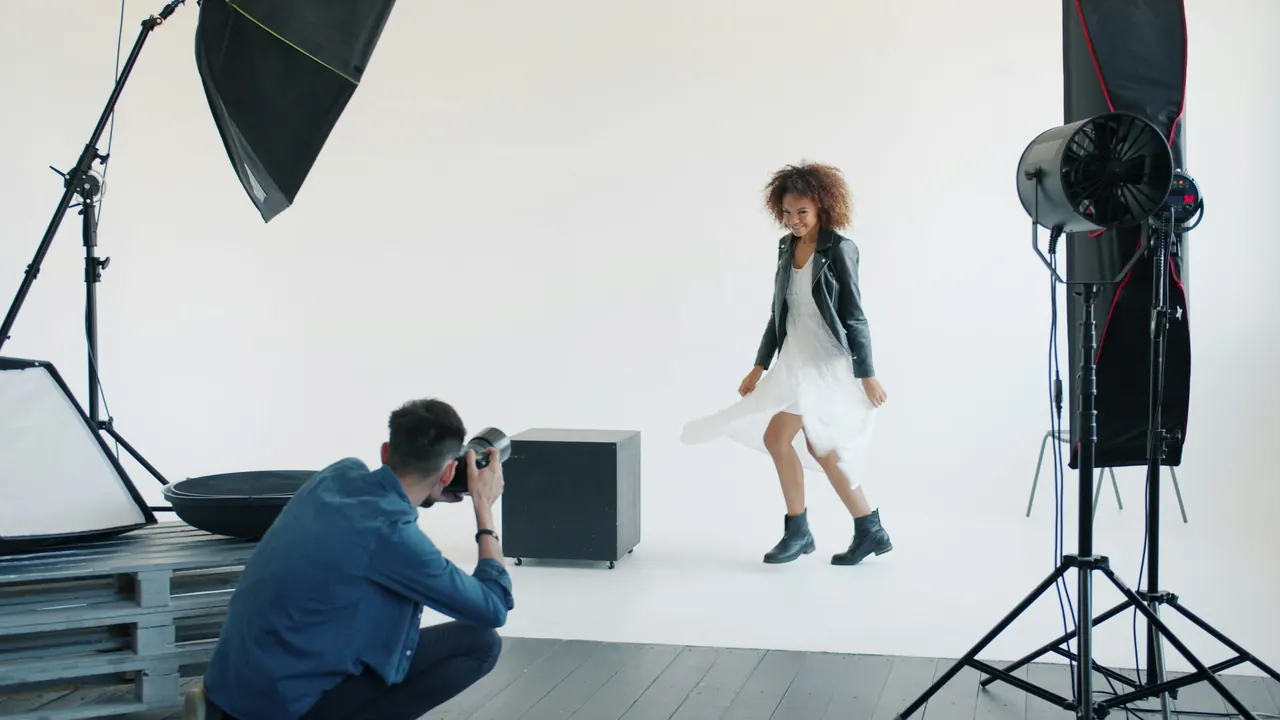 A photographer crouching to film a model twirling her dress