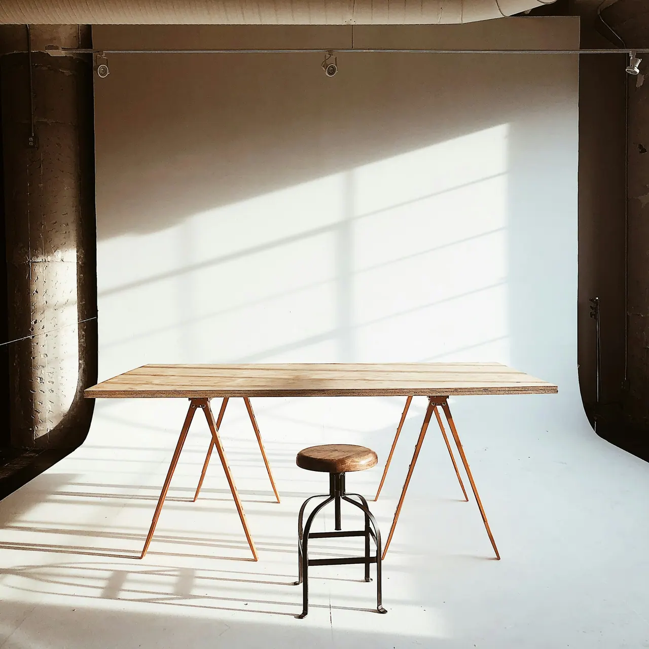Our sunlit studio, with a wooden table and a stool