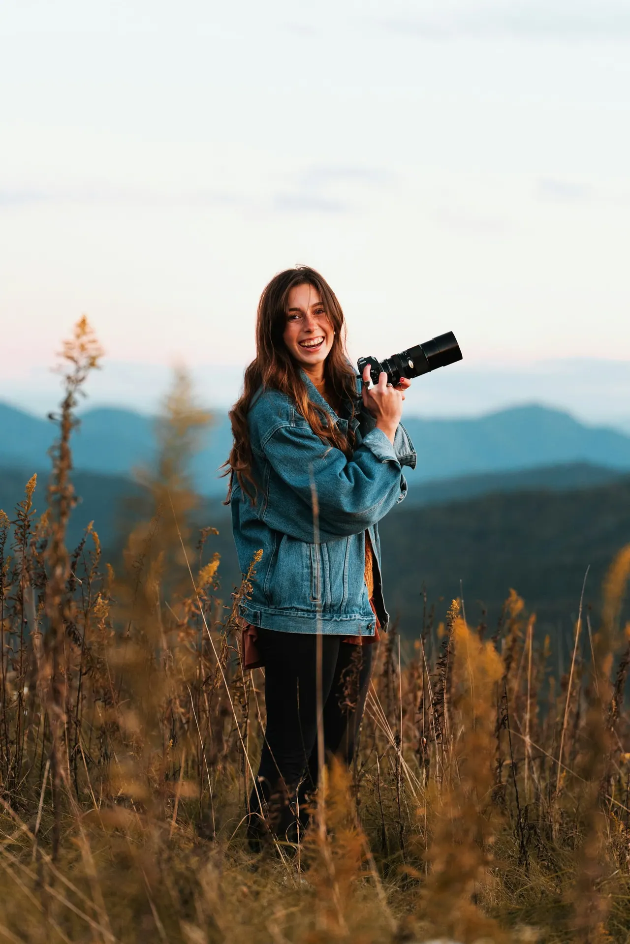 Our lead photographer laughing in a meadow with a camera in hand