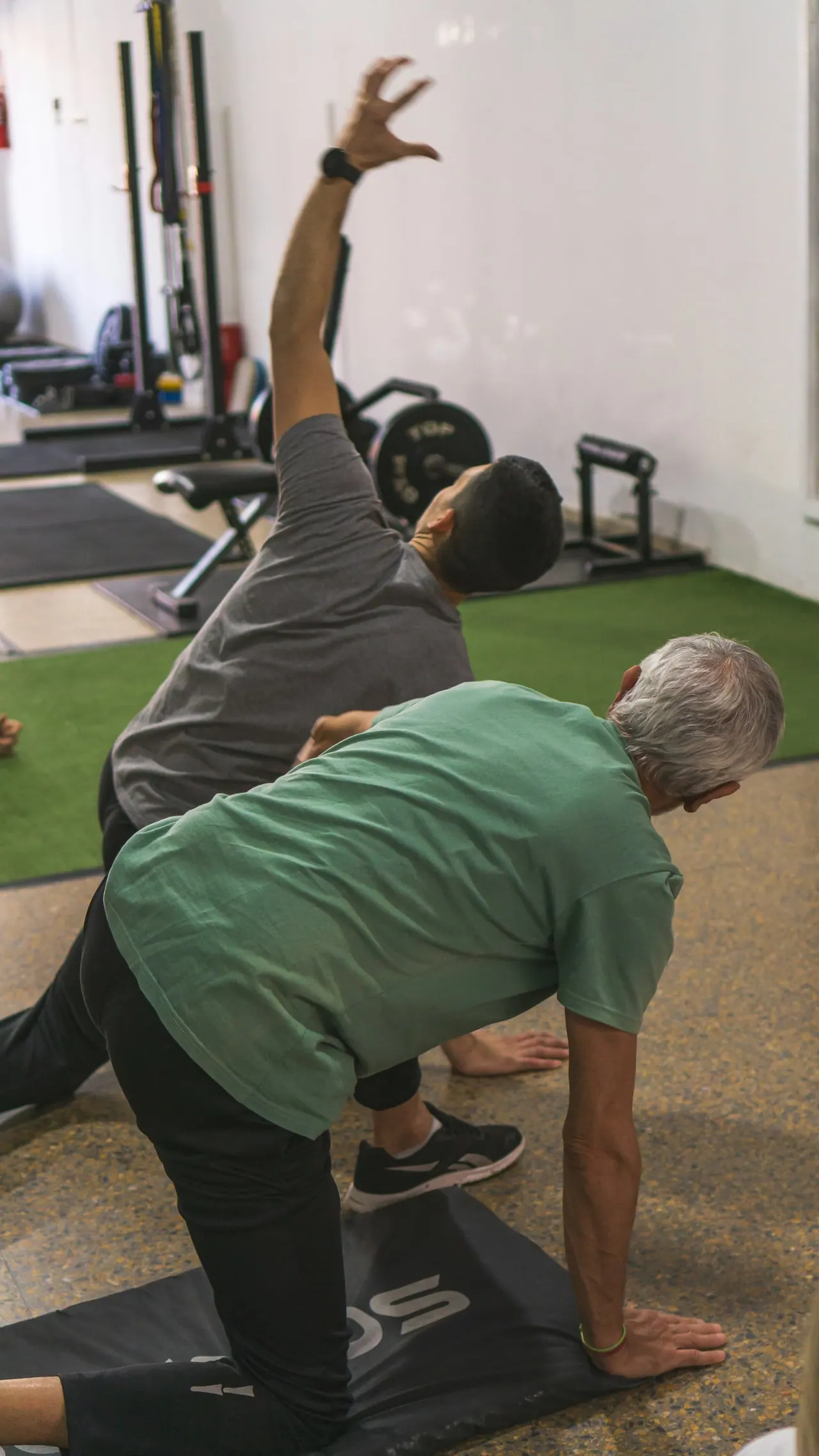 A coach guiding an older man through a slow side stretch