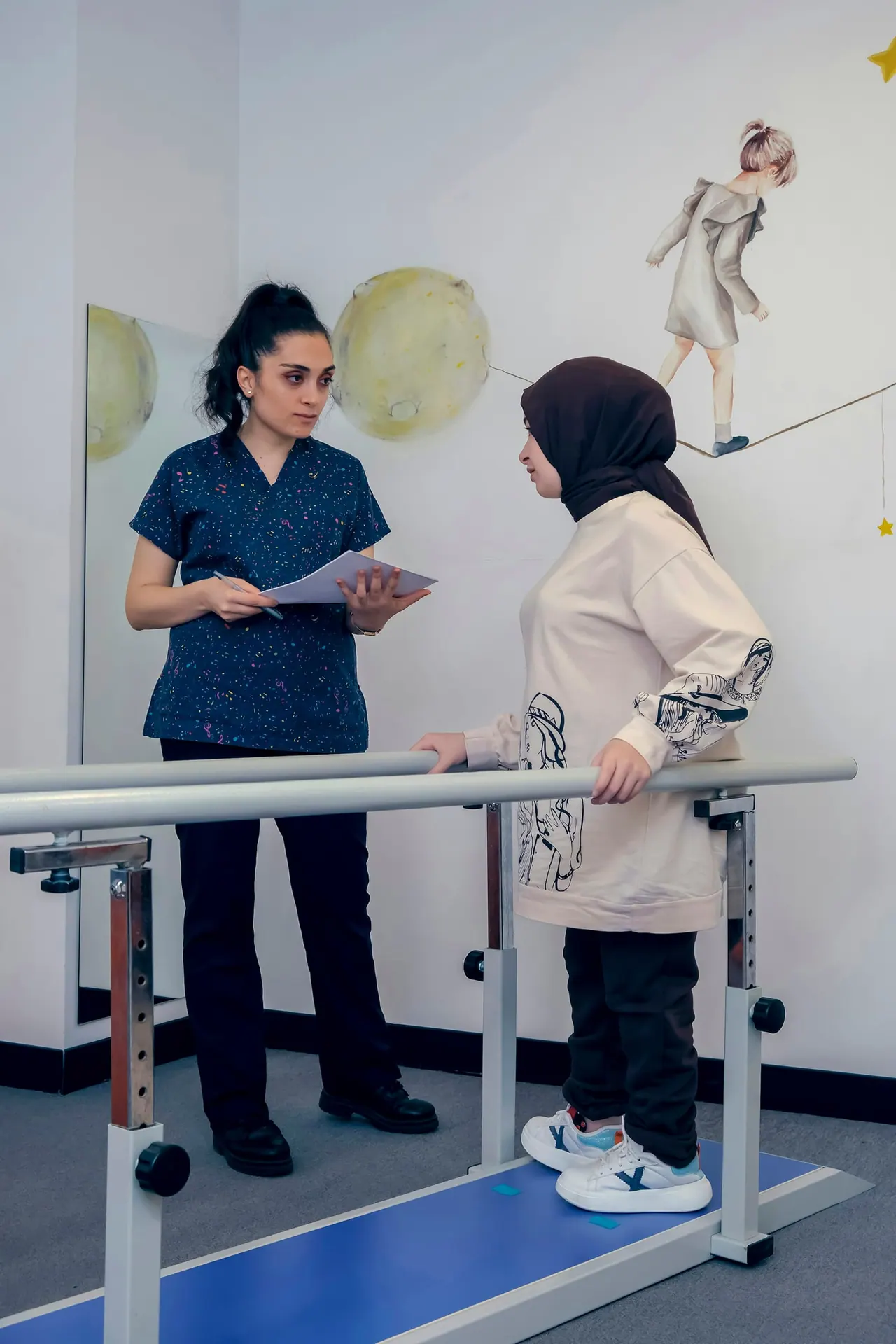 A physiotherapist with a clipboard beside a patient walking between parallel bars