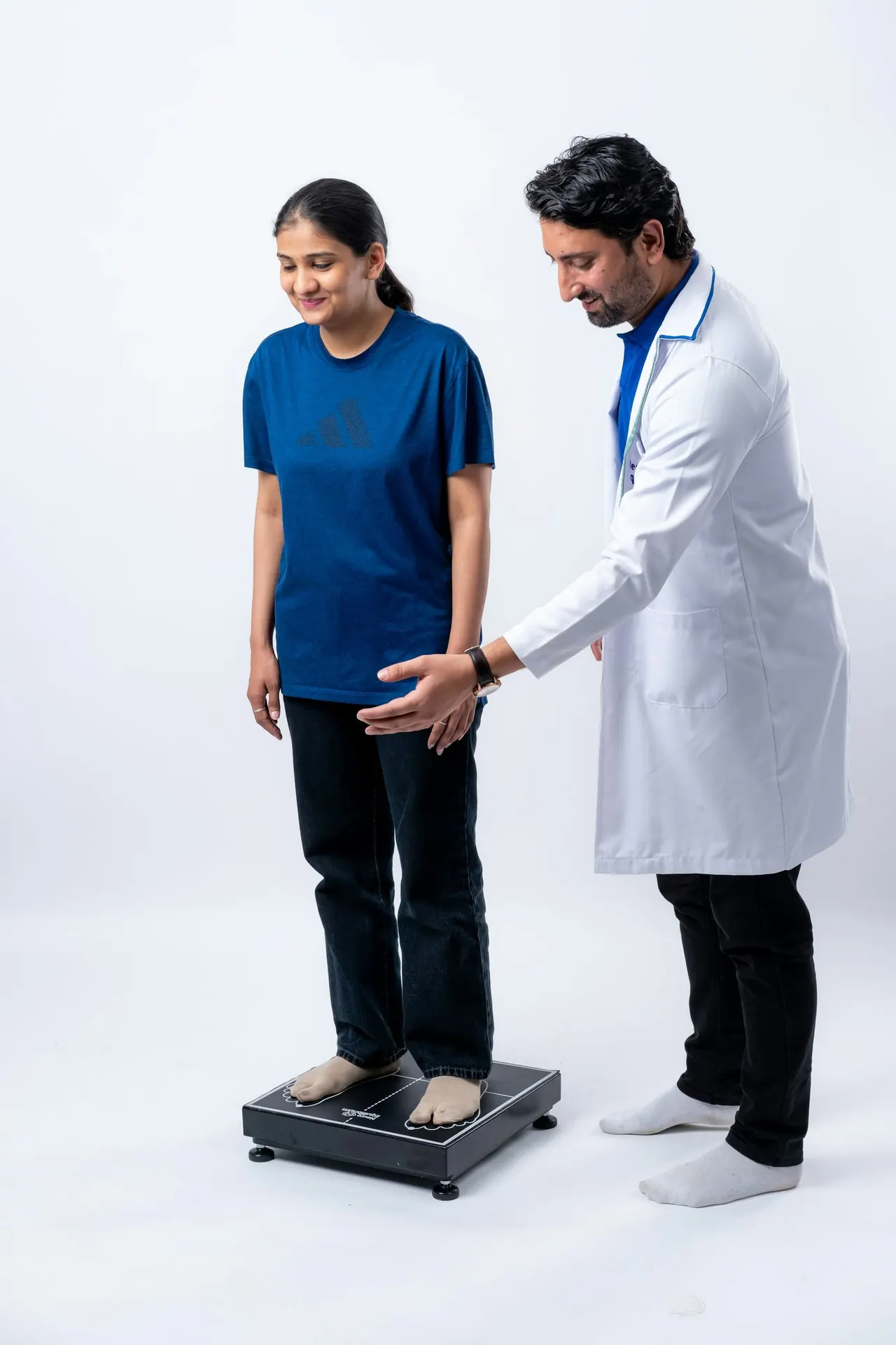 A physiotherapist checking a patient's stance on a balance plate