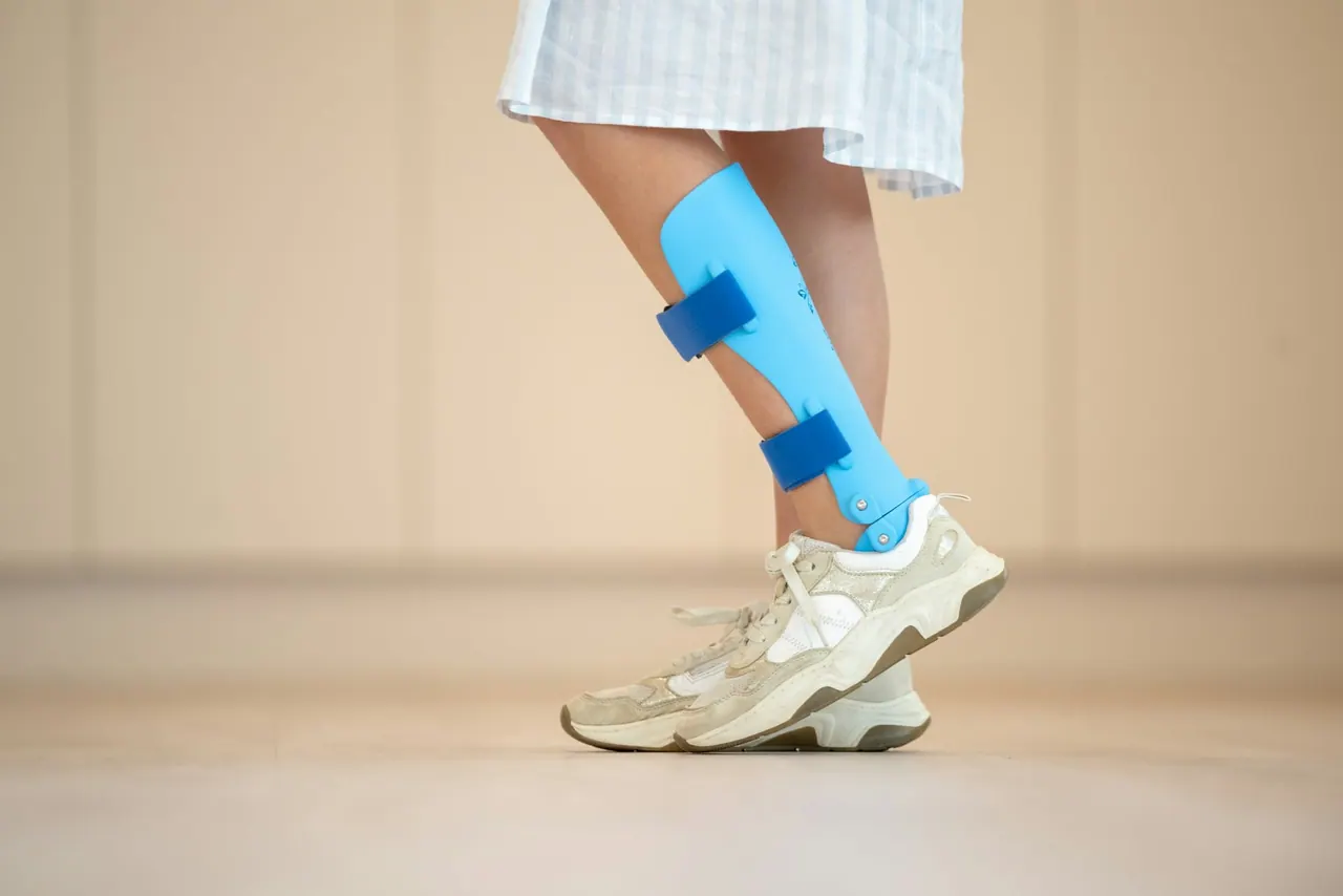 A leg in a light blue support brace taking a careful step