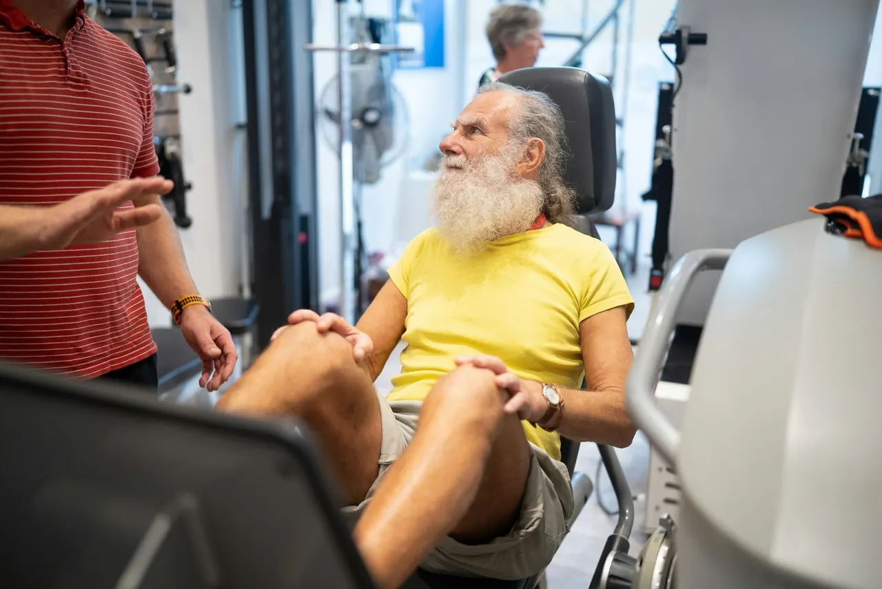 A physiotherapist coaching a smiling older man on a leg press