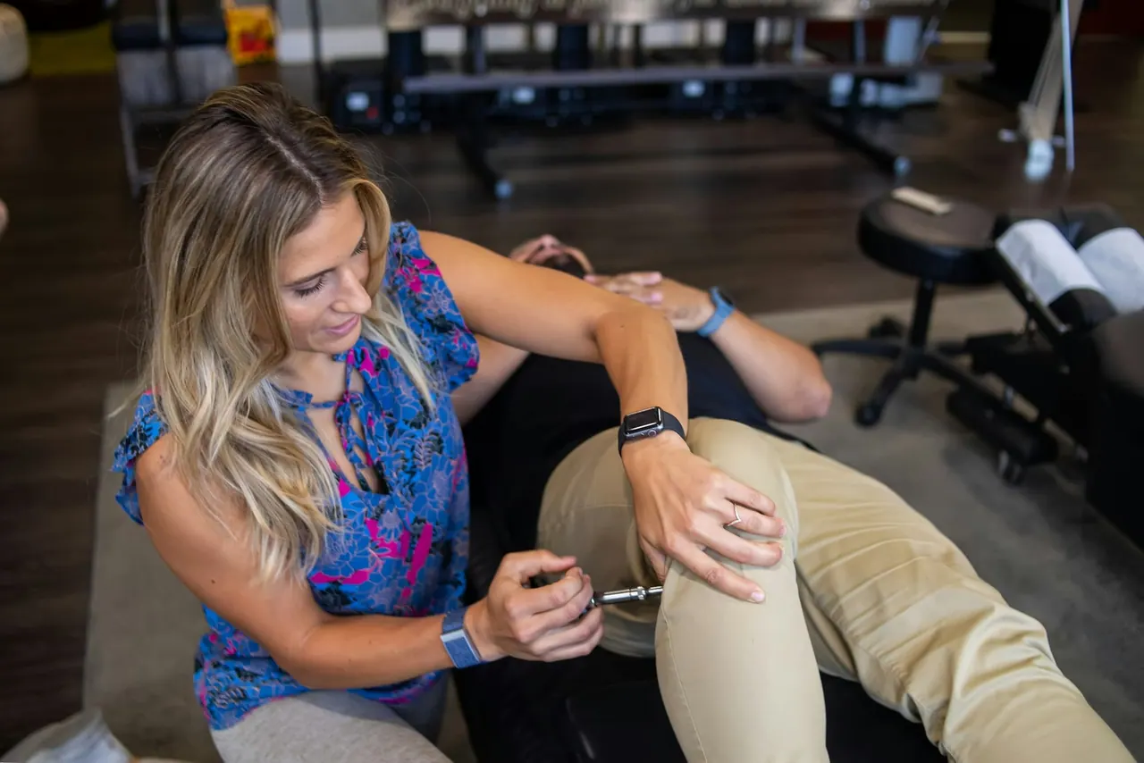 A physiotherapist gently testing a patient's knee in a calm studio
