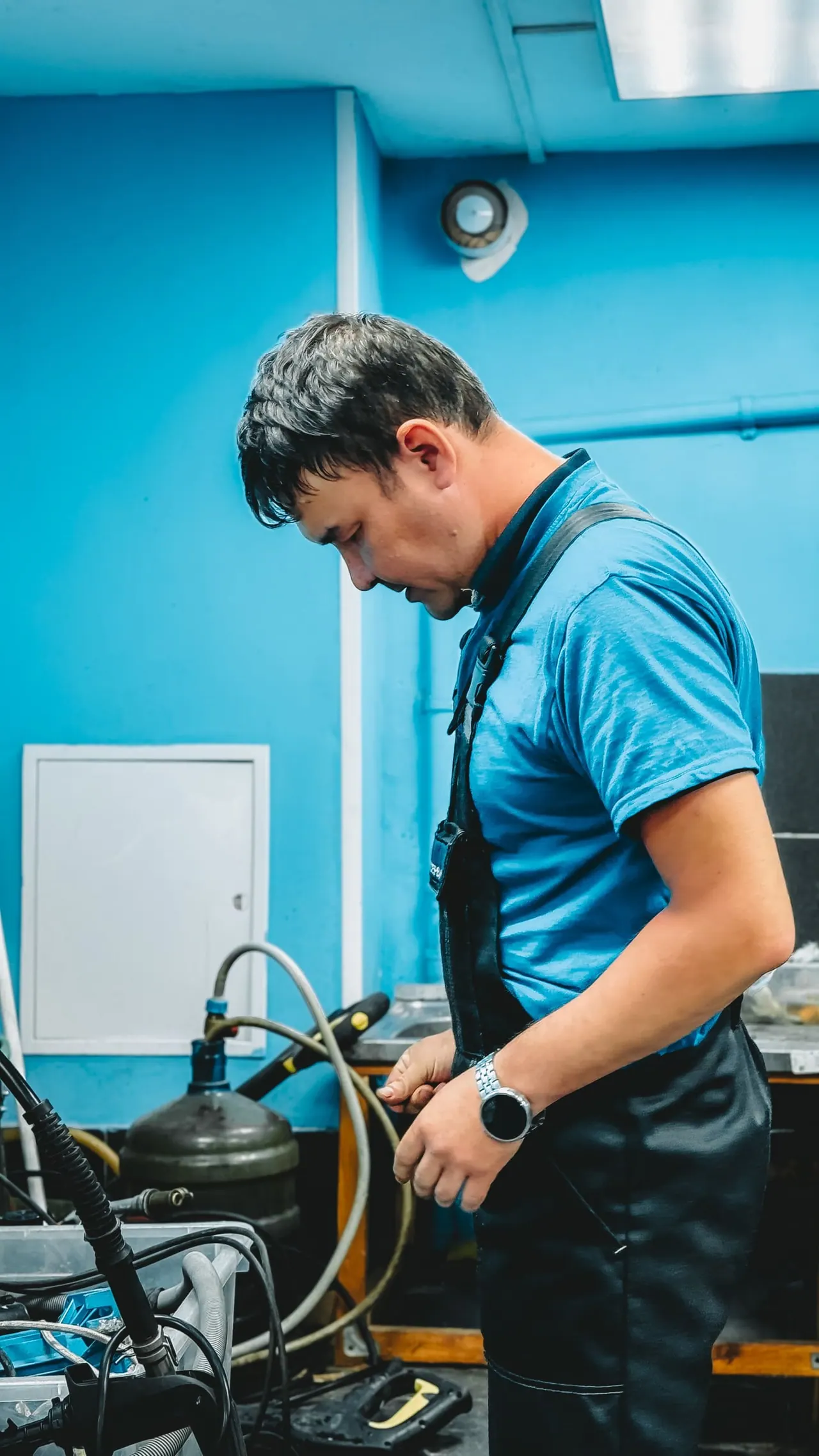 A technician checking equipment in a bright blue workshop